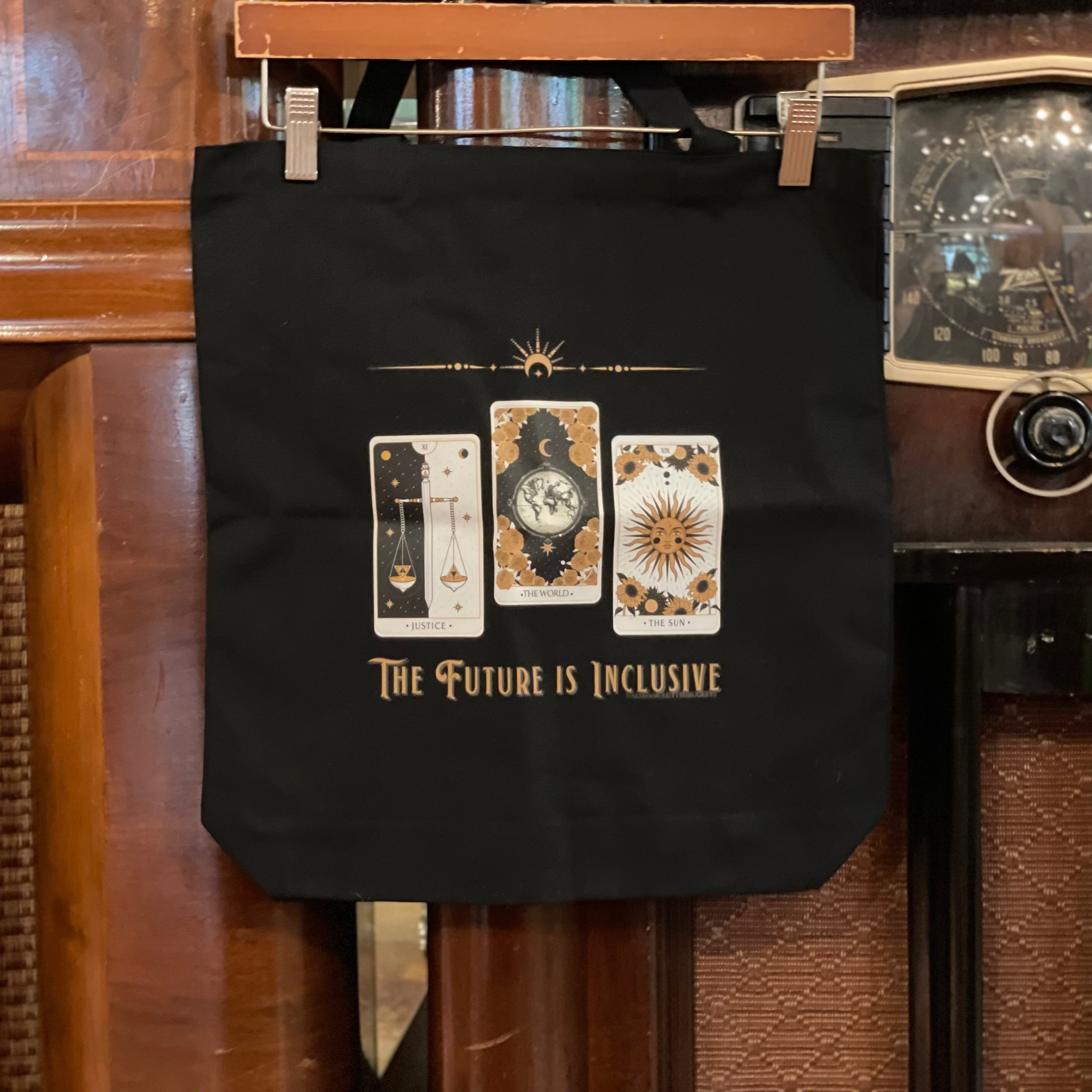 Black tote bag with tarot card design and 'The Future is Inclusive' text on a vintage radio.