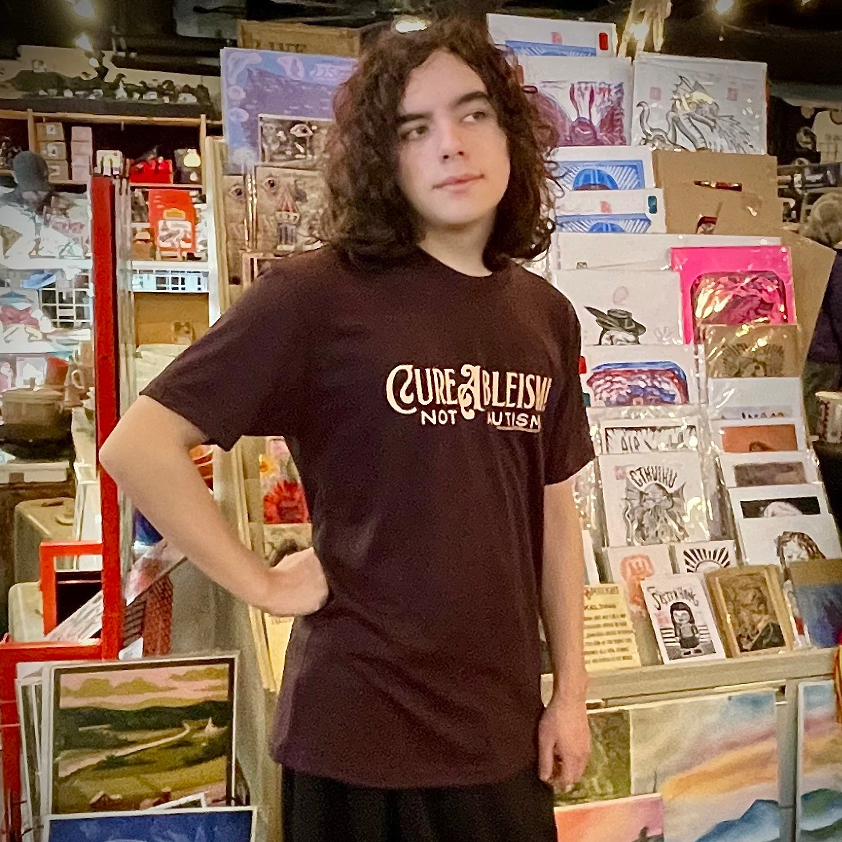 Person wearing a brown t-shirt with text in an art store